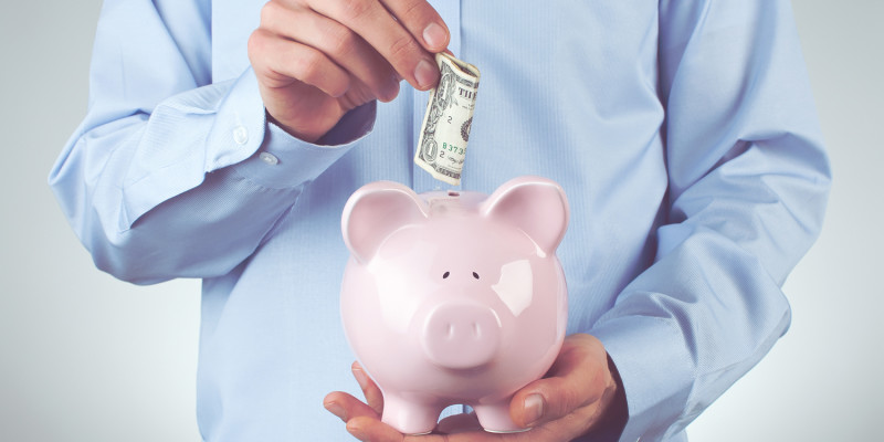 Male hand putting coin into a piggy bank